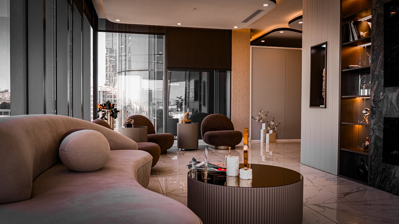 A stylish modern living room with sleek furnishings and panoramic city views from tall windows.